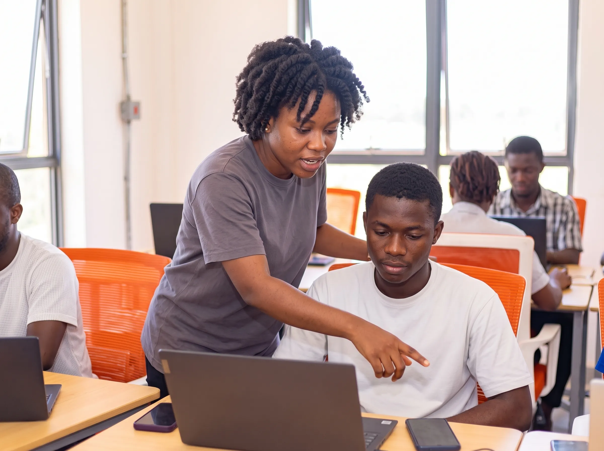 Une mentore accompagne un participant devant son ordinateur, en salle de formation.